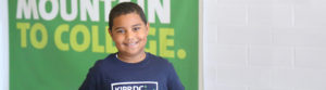 KIPP DC student standing in front of a green banner