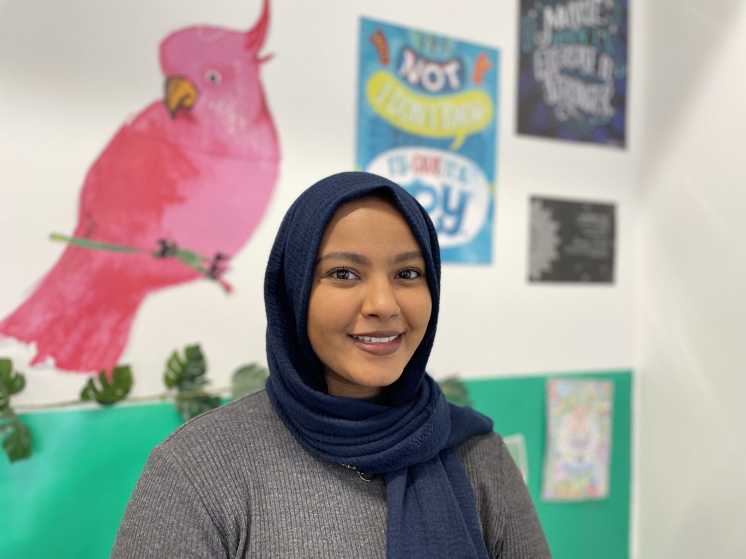 Ms. Taha smiling into camera inside her classroom