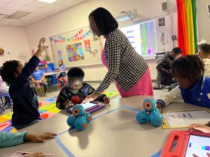 Ms. Dionne Cooley is assisting her students with technology in her classrom.