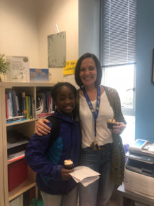 Erin Huseby smiling into the camera with one of her students