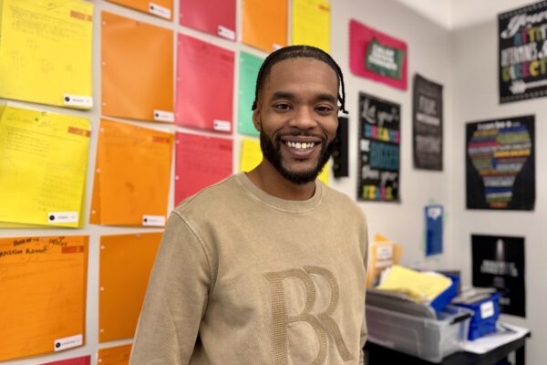 Mr. Miles Edwards smiling into the camera inside his classroom