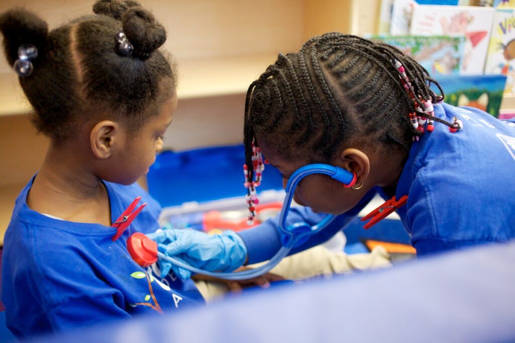 Two KIPP DC students playing. One acting as a Dr. listening to the other's heart beat.